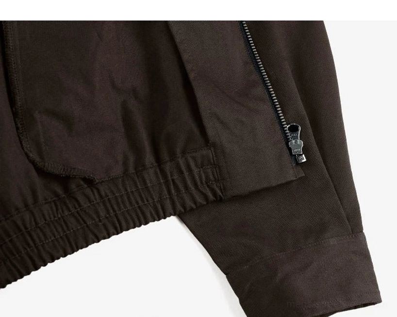 Side detail of the cotton Harrington jacket showing the metal zipper pocket, elasticated hem structure, simple sleeve, and functional streetwear construction
