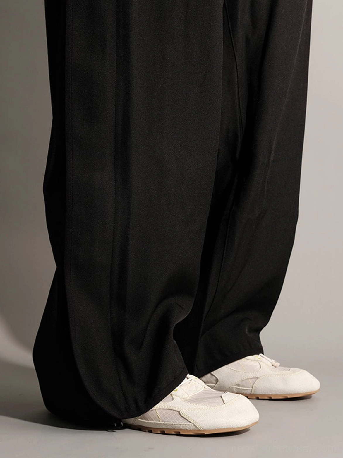 Cream off-white paneled low-profile trainers with subtle stitching and tan gum outsole styled with wide-leg trousers