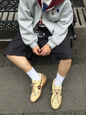 Cream star retro running sneakers styled with gray hoodie pinstripe shorts and white crew socks in a casual streetwear outfit