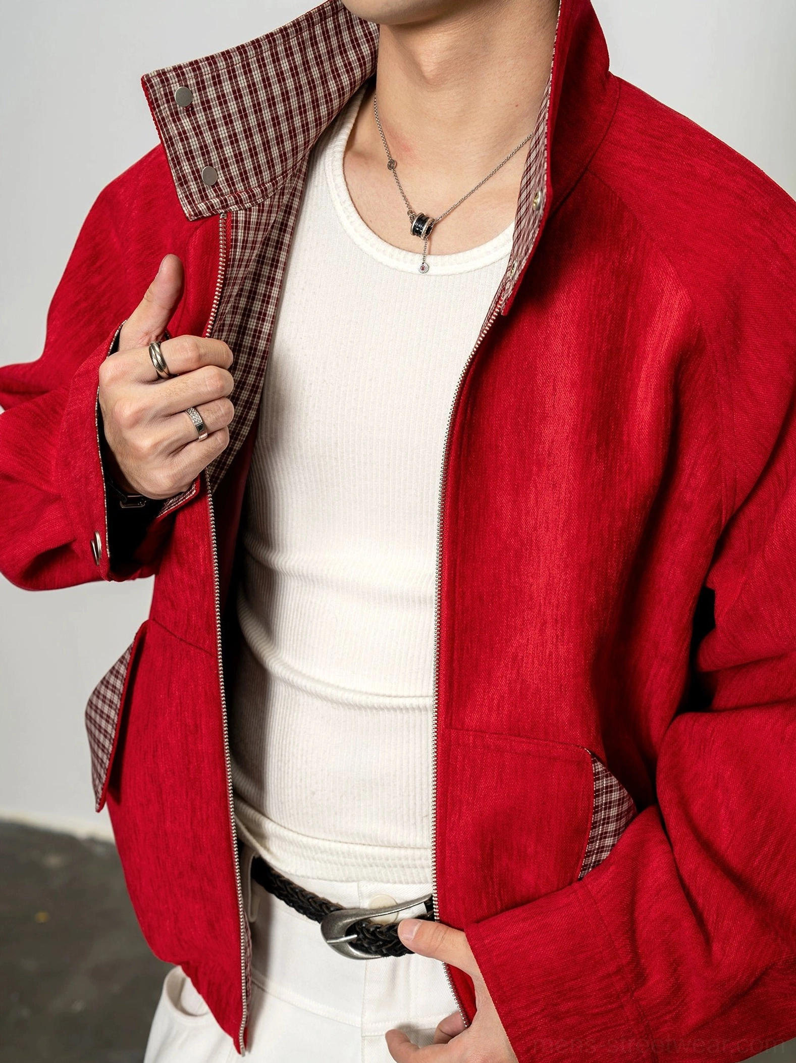 Close-up of crimson red men's cropped zip jacket with stand collar, plaid lining, silver zipper and white tank top