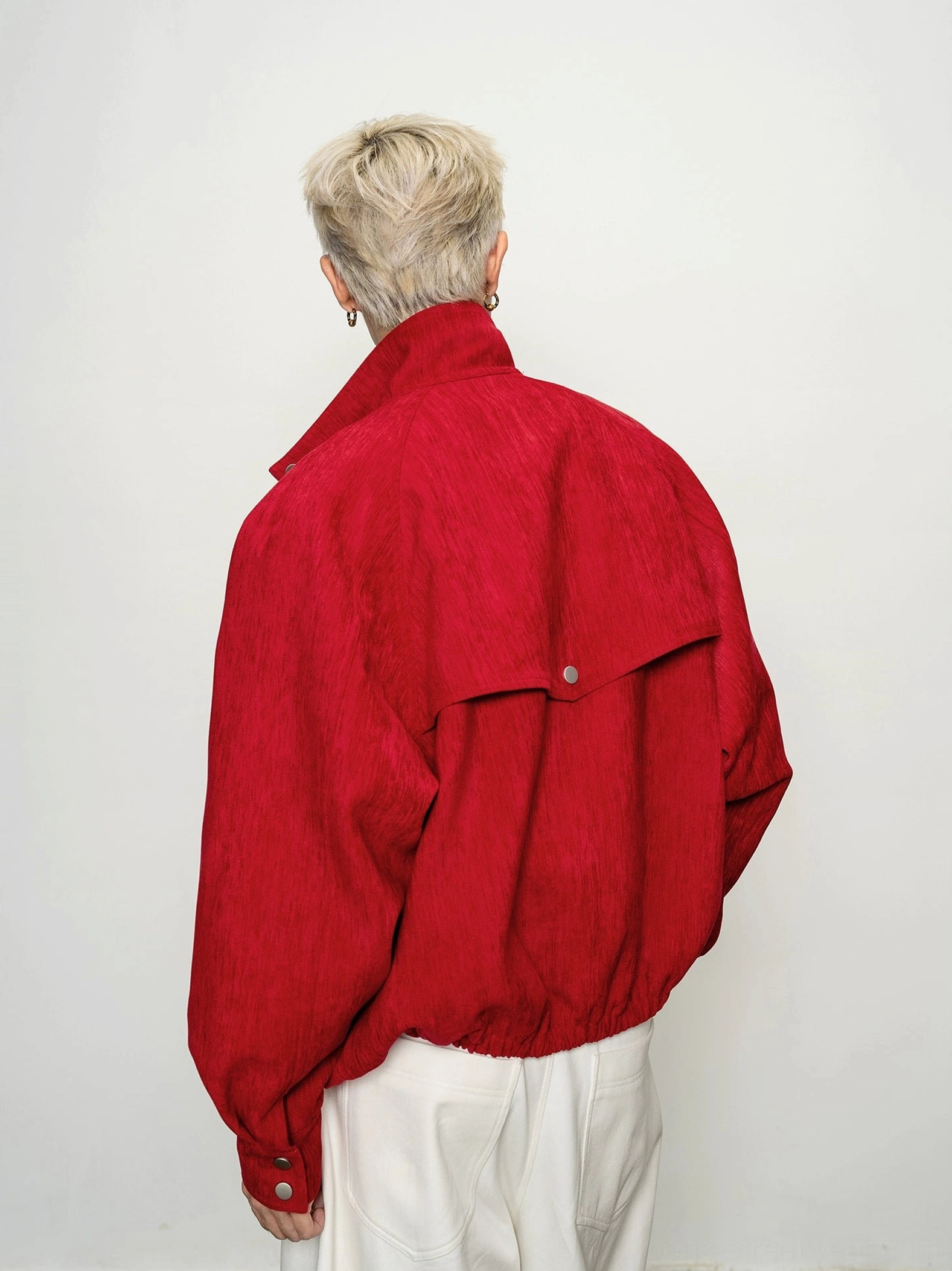 Back view of men's crimson cropped bomber jacket showing elasticated hem and snap-button rear flap detail