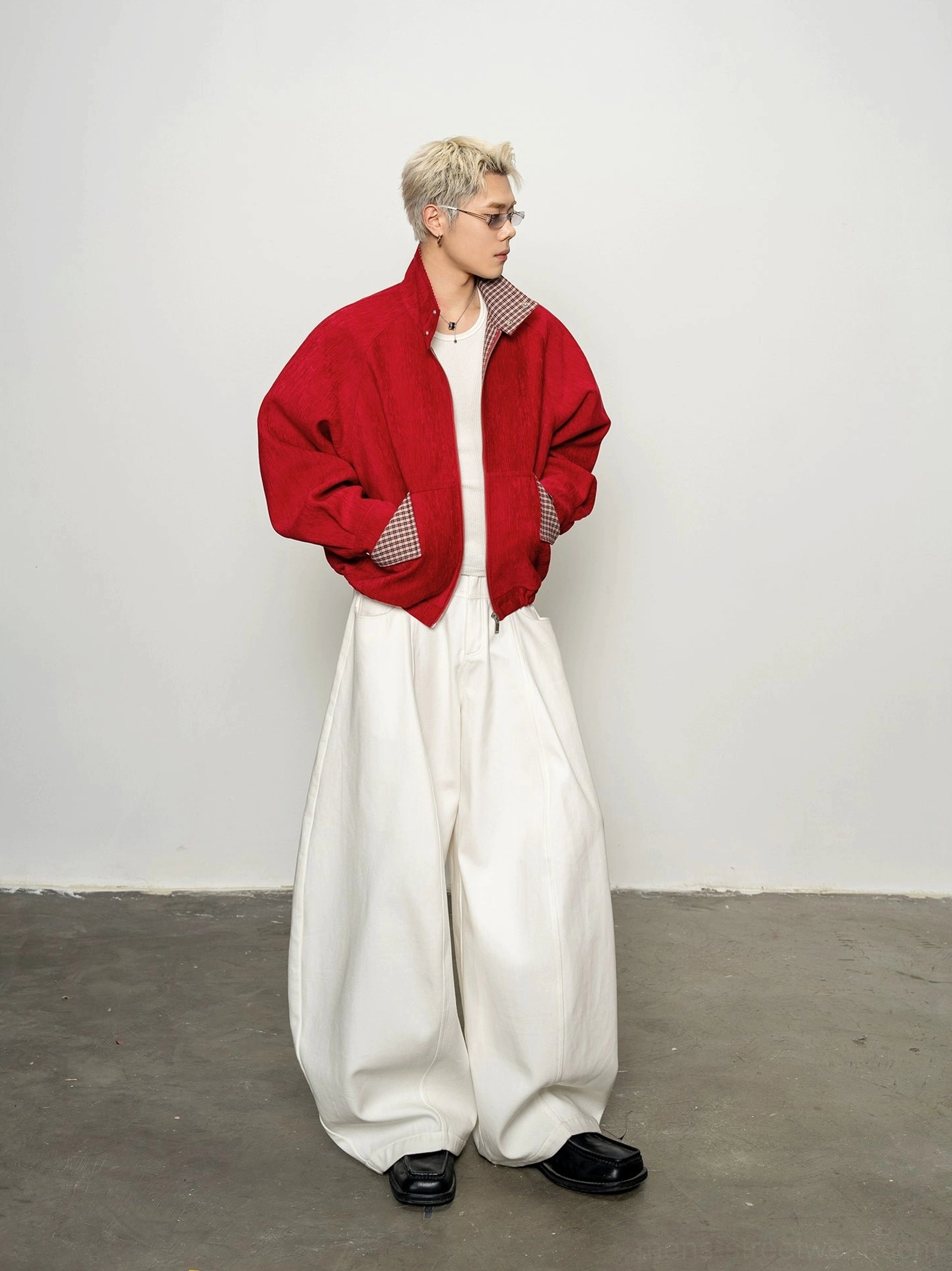 Men's crimson red cropped bomber zip jacket styled with white wide-leg trousers in a minimalist studio front view