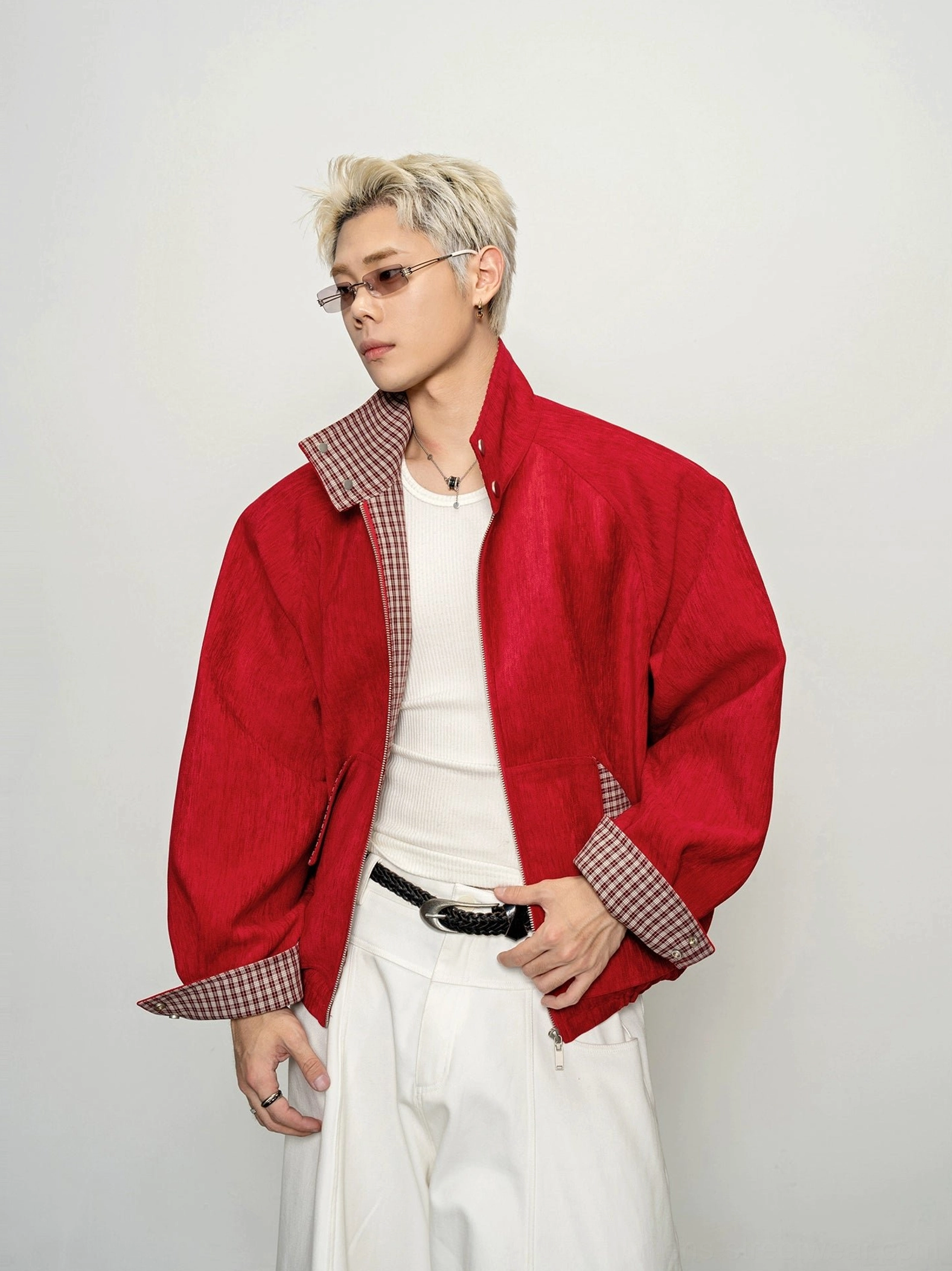 Three-quarter front view of oversized crimson cropped bomber zip jacket with rolled plaid cuffs and front pockets