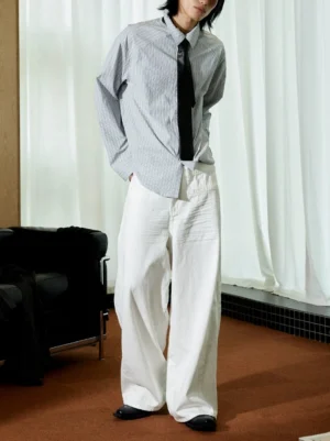 Crisp white pleated wide-leg balloon cotton trousers side view styled with striped shirt and black tie