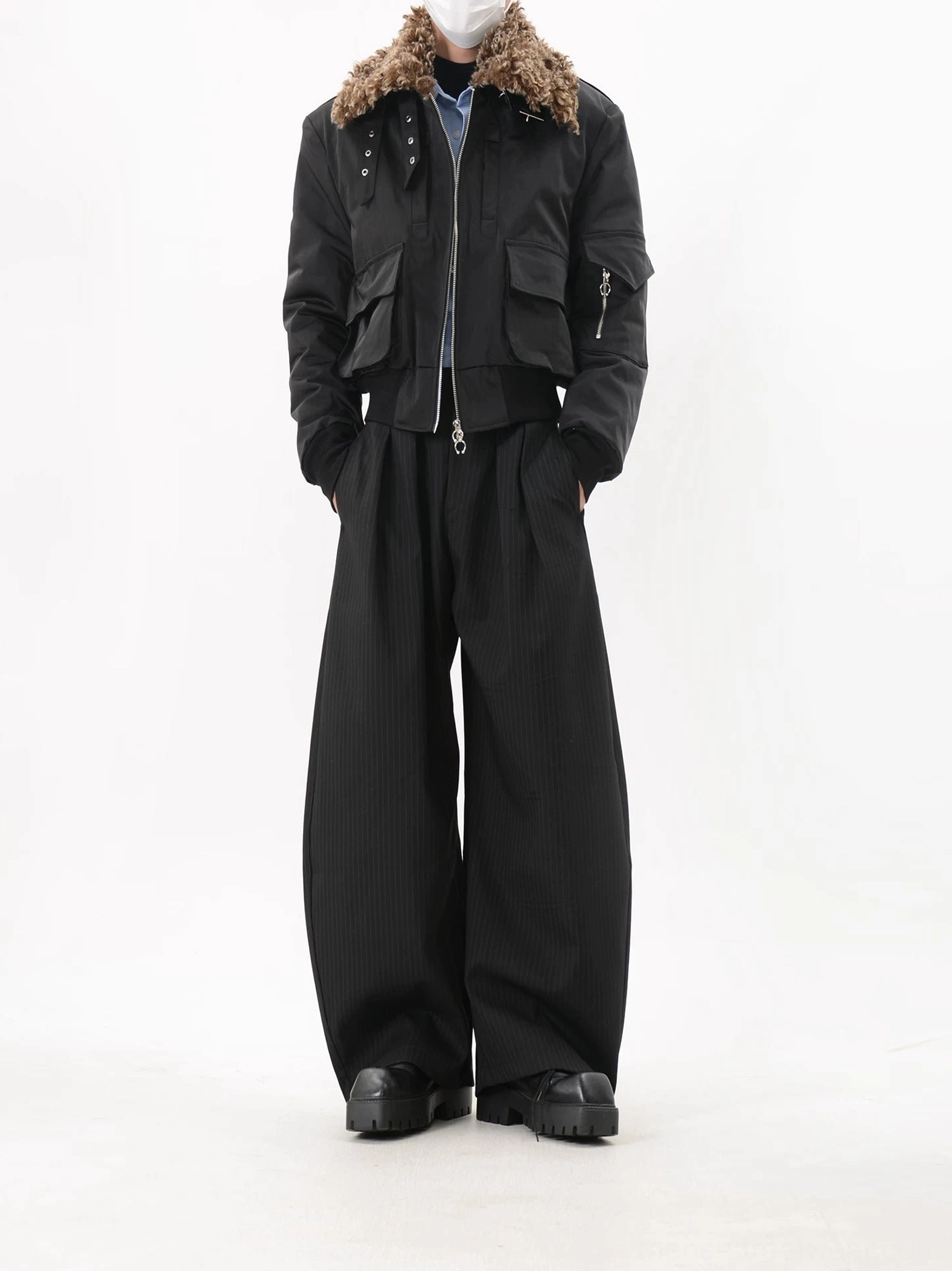 Low-angle front view of men's cropped black faux fur collar bomber jacket with sleeve zip pocket, utility details and modern Korean streetwear styling