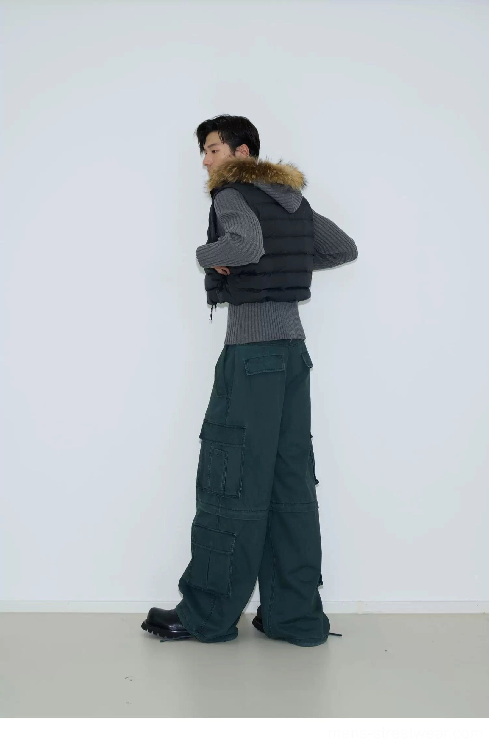 Cropped quilted puffer vest layered with a fur trimmed hooded garment and cargo pants from a side back view