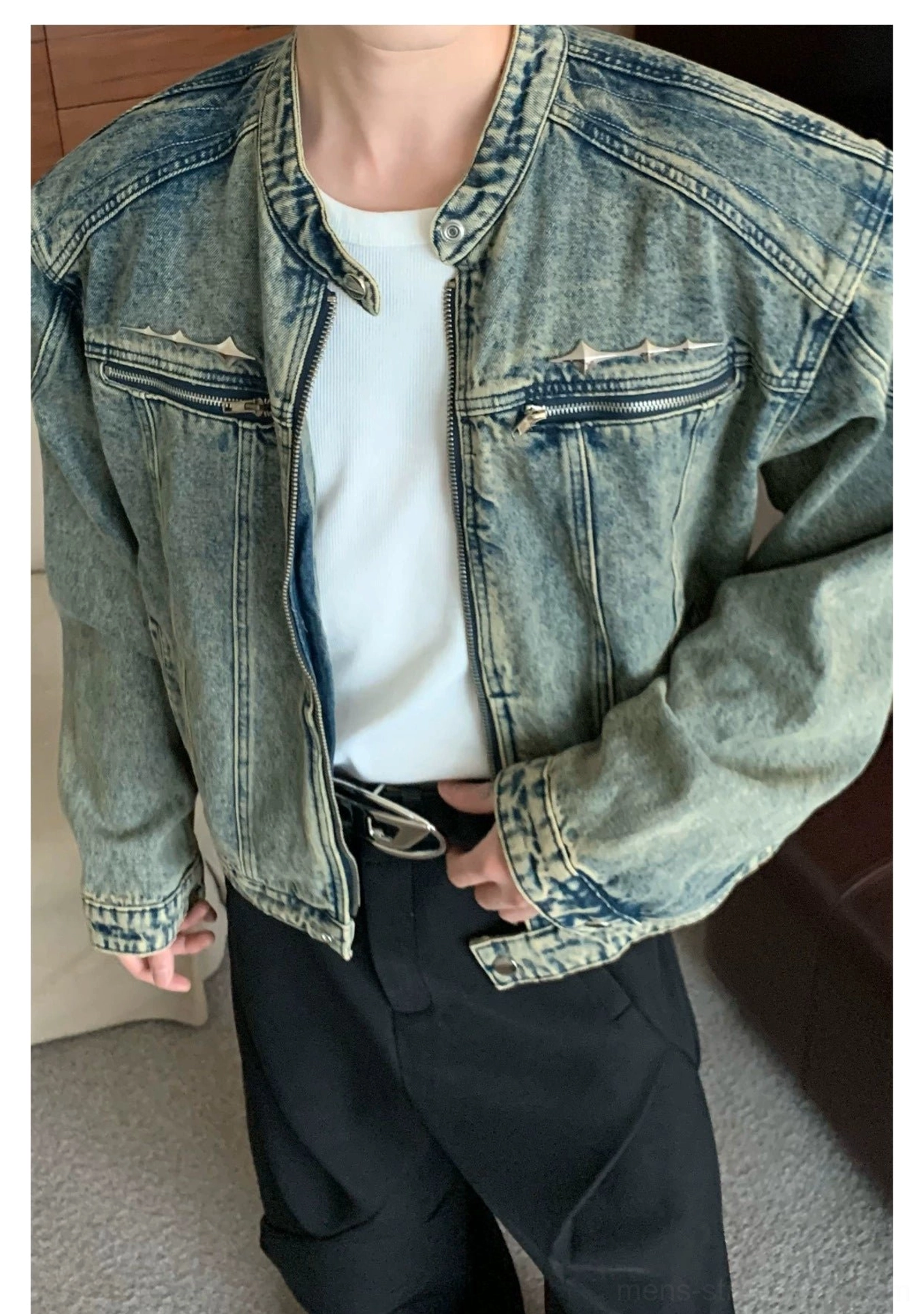 Detailed view of distressed blue cropped denim moto jacket with stand collar and front zipper pockets