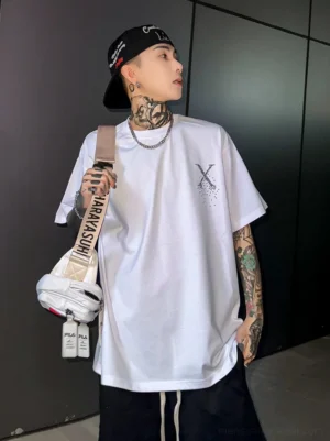 Front three-quarter view of an oversized white Pixel X graphic streetwear T-shirt with scattered left chest artwork and relaxed short sleeves