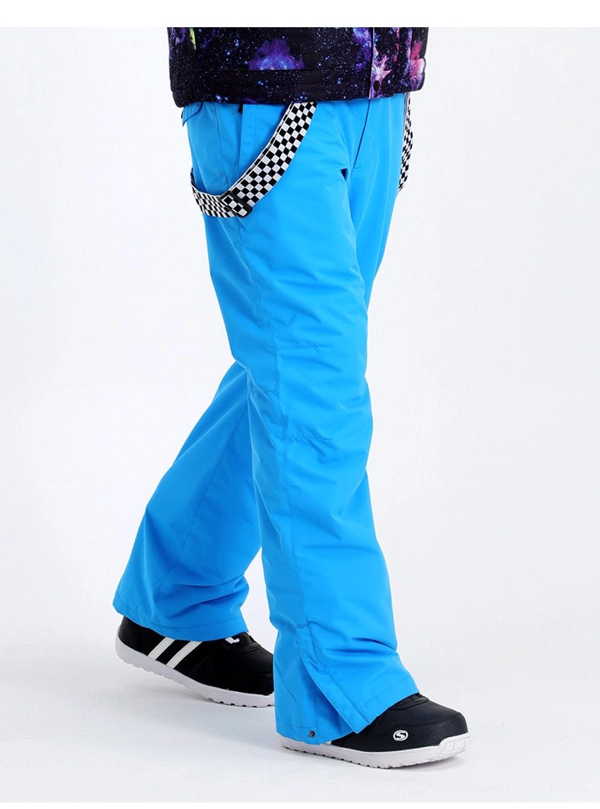 Bright cyan blue checkerboard suspender snow pants shown from the side with a printed winter jacket