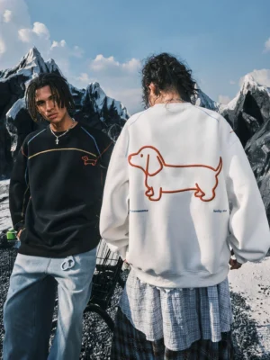 Black and white dachshund embroidered oversized crewneck sweatshirts styled as relaxed Seoul streetwear against a snowy mountain landscape