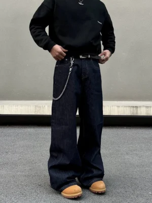 Dark blue baggy wide leg denim jeans styled with a black sweatshirt, metal waist chain, and wheat work boots