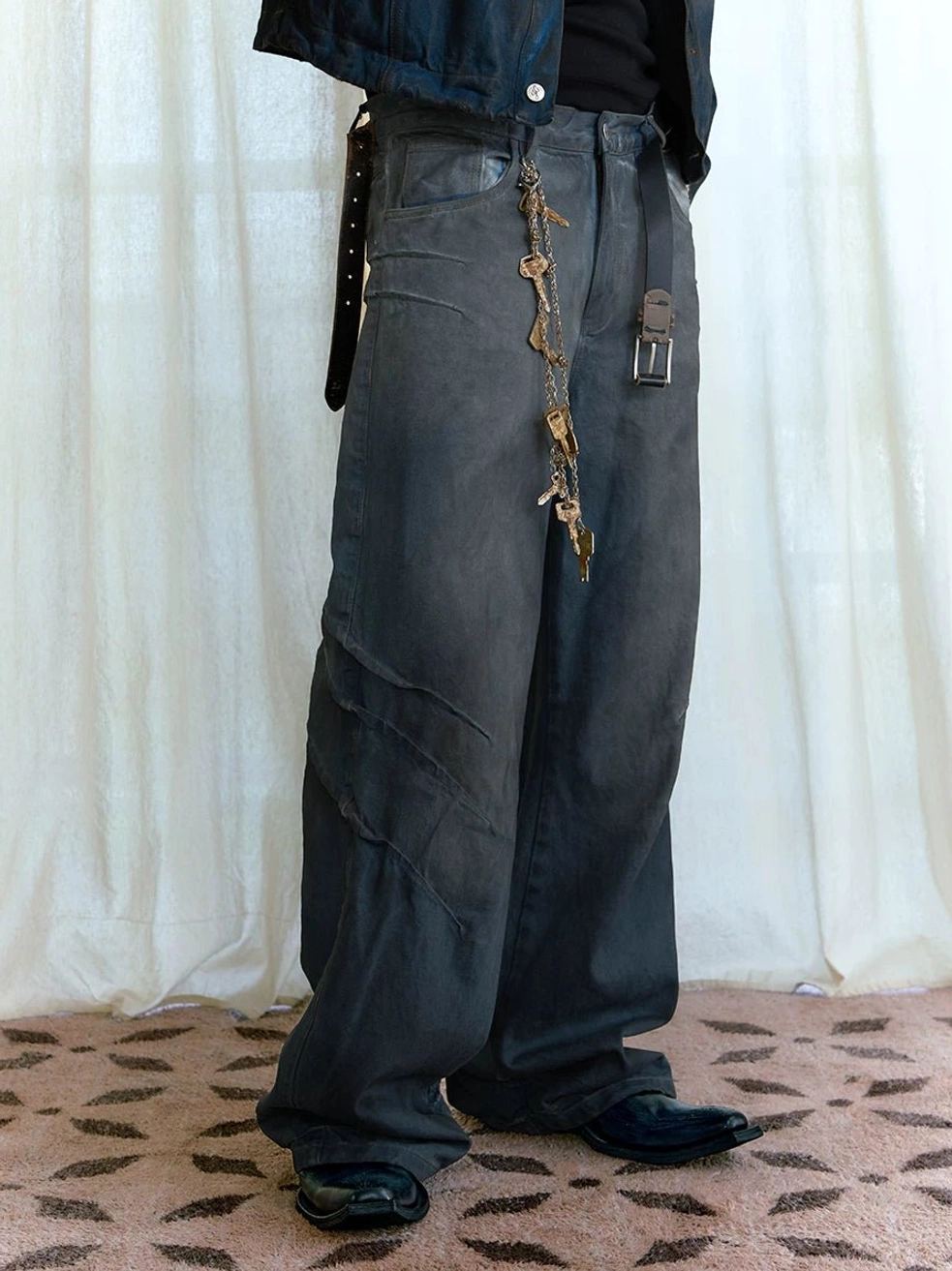 Close front view of dark blue distressed stacked wide-leg jeans with twisted 3d seam details and waist chain styling
