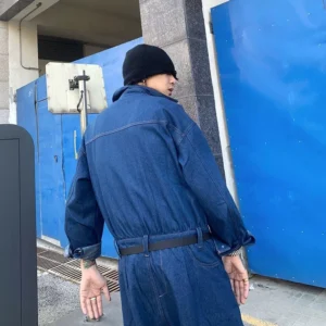 Dark blue oversized denim boiler jumpsuit back view showing adjustable belt relaxed workwear fit and full length silhouette