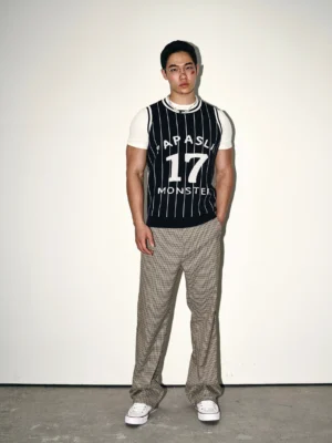 Dark blue pinstripe varsity knit basketball jersey vest layered over a white t-shirt with checkered trousers in a full-body streetwear outfit