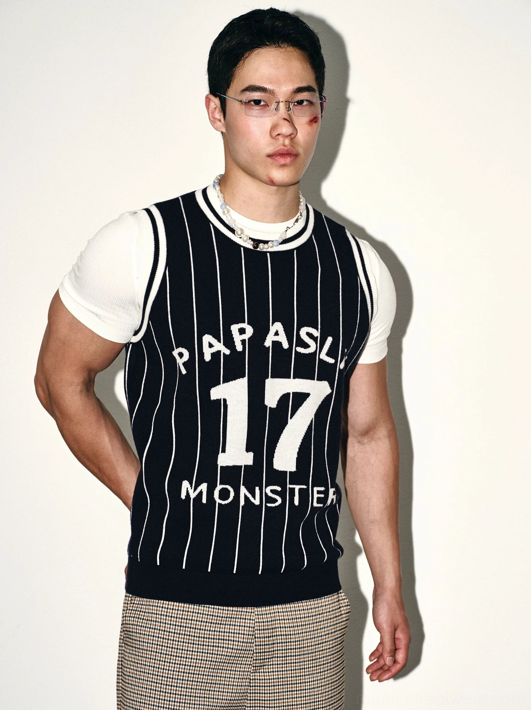 Three-quarter view of dark blue pinstripe varsity knit jersey vest showing ribbed crew neck and collegiate front graphic