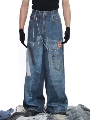 Front view of oversized dark blue reconstructed denim jeans featuring multi-panel patchwork, vintage fading, ultra-wide legs, and distressed workwear details
