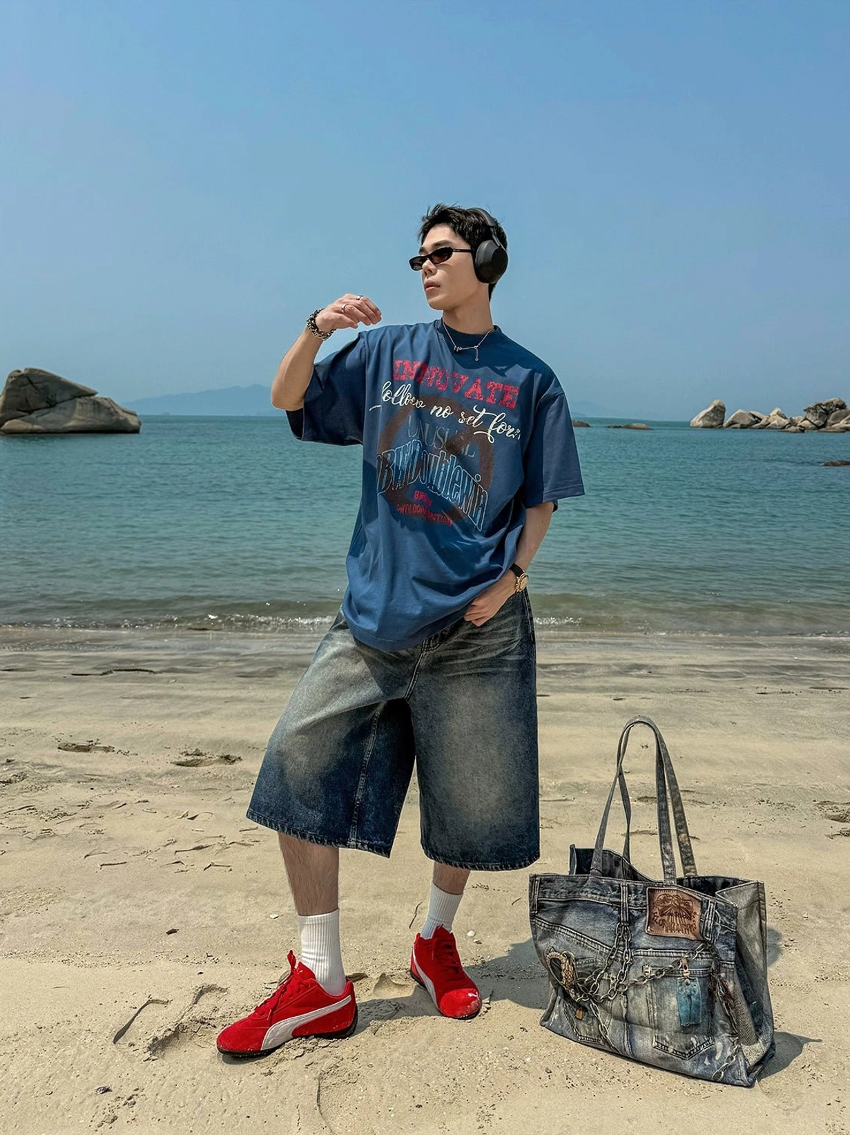 Dark blue vintage wash oversized denim culotte shorts in coastal streetwear outfit with graphic tee