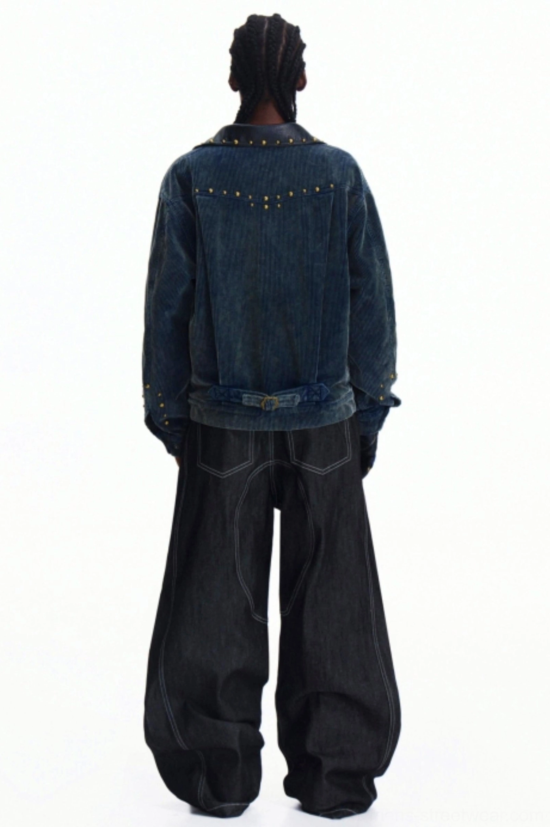 Rear view of a dark blue denim layered outfit showing wide-leg jeans and a studded denim trucker jacket with contemporary streetwear styling