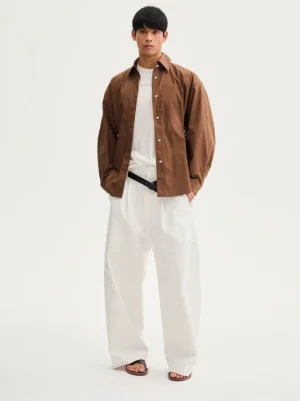 Dark brown oversized long sleeve cotton button-down shirt styled with a white tank and wide-leg pants