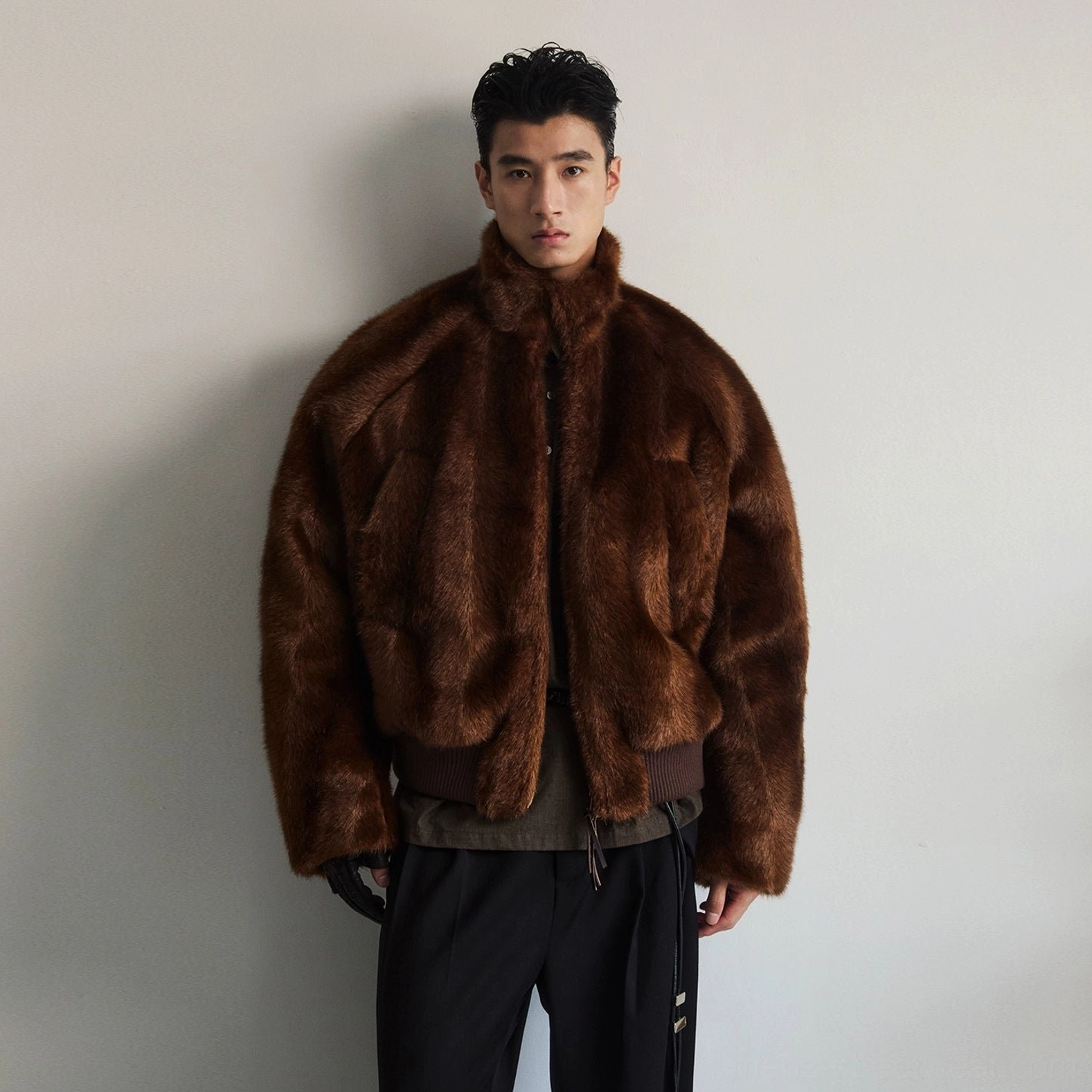 Full front view of dark brown oversized faux fur bomber jacket with cropped relaxed shape ribbed hem and minimalist zipper closure