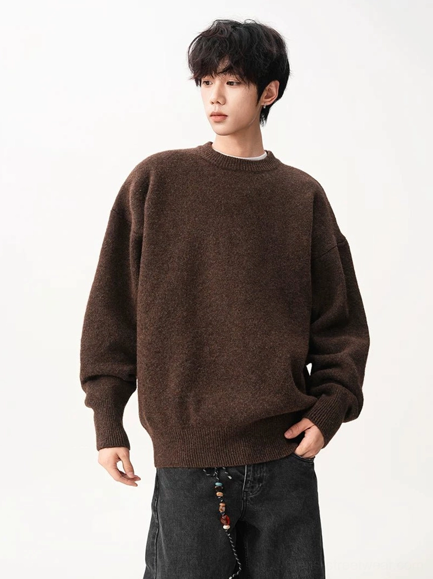 Three-quarter view of a dark brown relaxed oversized knit sweater with ribbed cuffs and waistband in a minimalist streetwear studio look