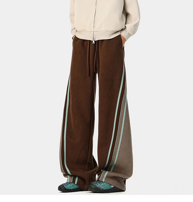 Back view of dark brown wide-leg varsity track pants with contrast side stripe and color-block detailing