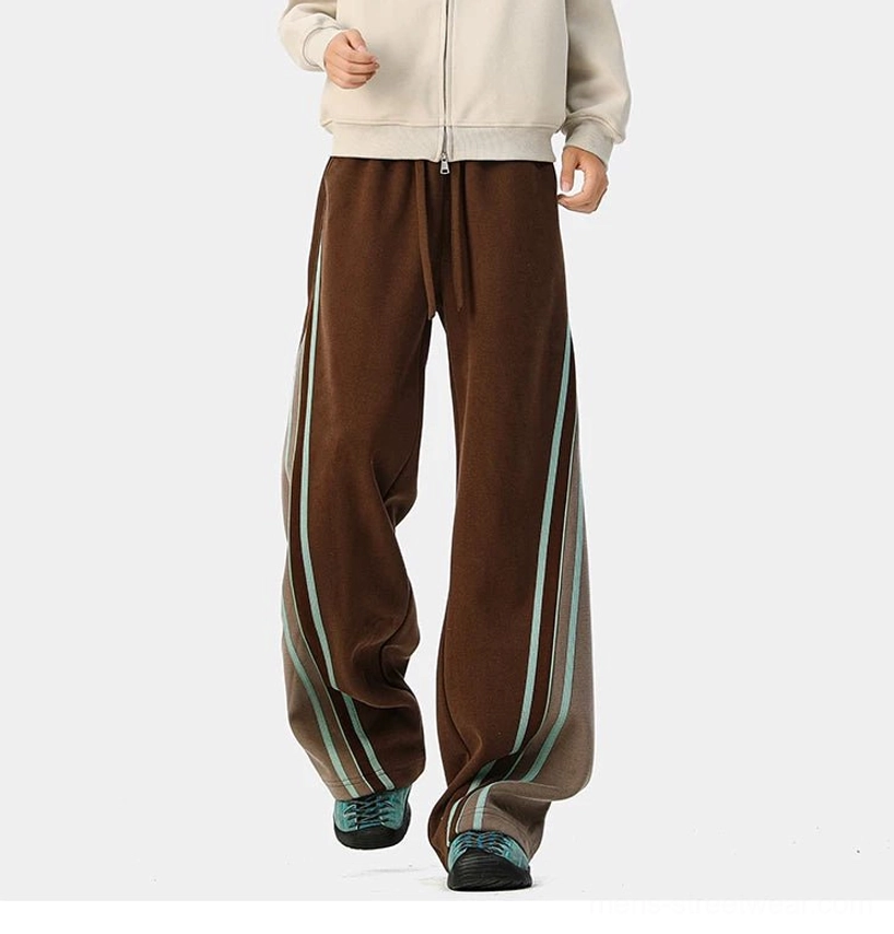 Dark brown wide-leg varsity track pants with matching side color block and light cyan stripes styled for casual streetwear