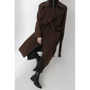 Side profile of a male model in a relaxed dark brown wool trench coat with double-breasted styling and a long waist belt