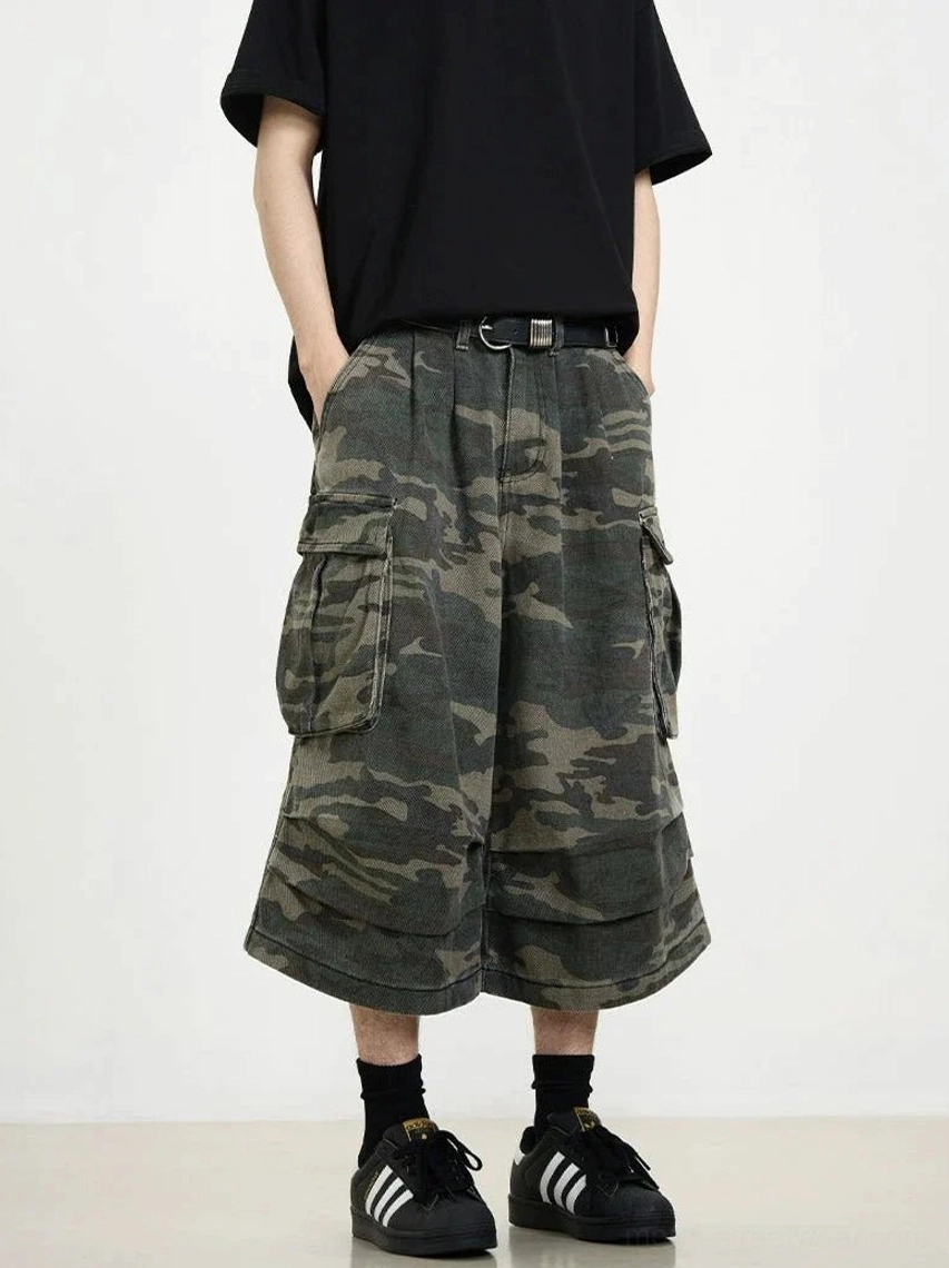 Side front view of dark camo cargo shorts with belt loops, oversized utility pockets, and contemporary wide cropped legs