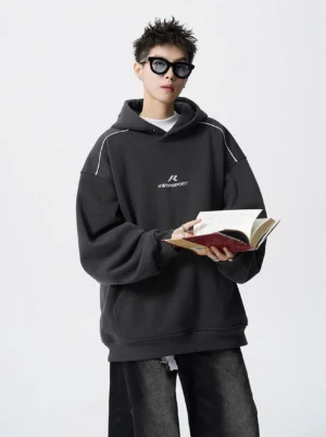 Dark charcoal gray oversized fleece hoodie with white shoulder piping, embroidered chest detail, and relaxed Seoul streetwear silhouette