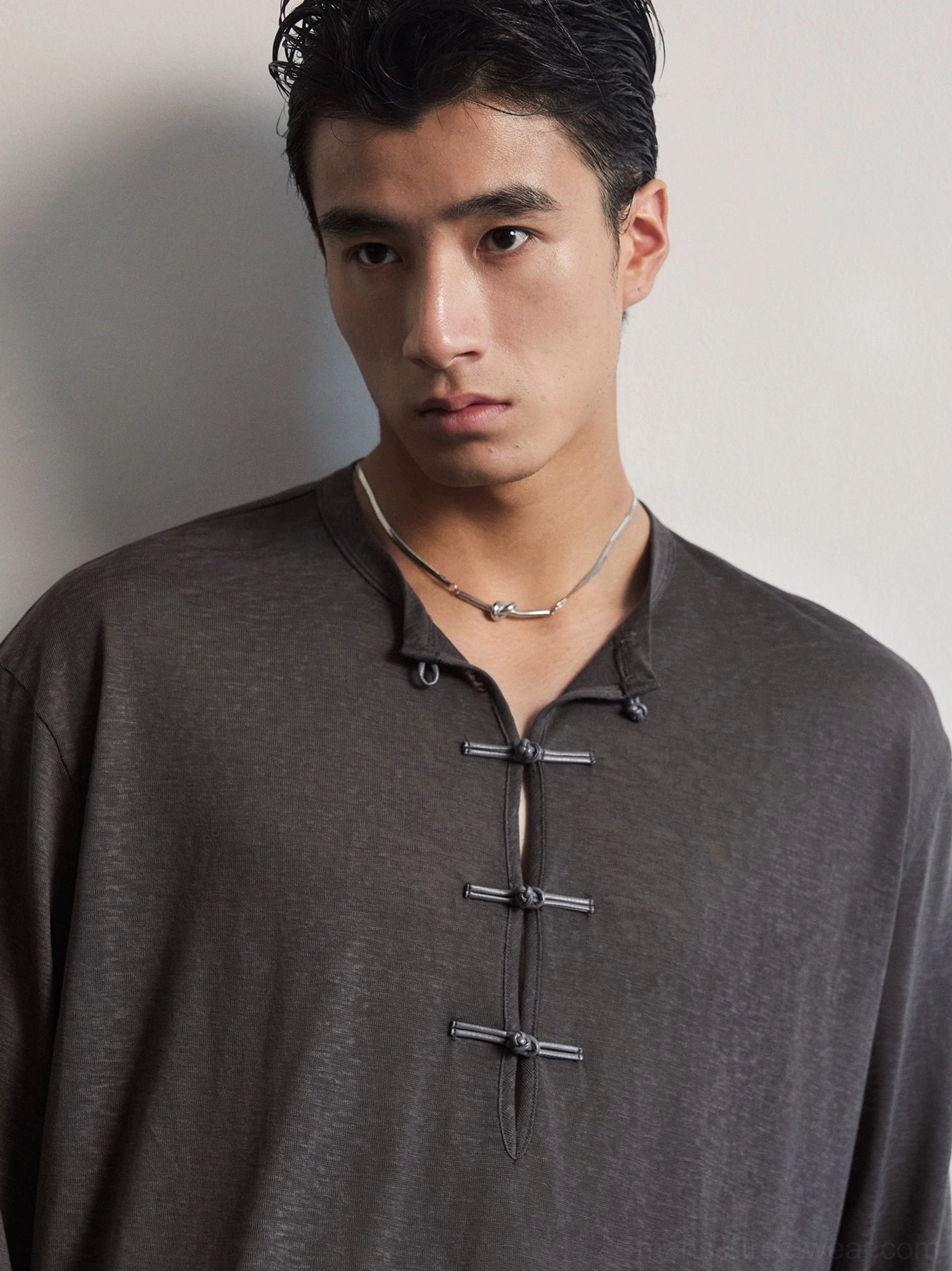 Close up of dark charcoal silk blend Henley tee showing three Chinese inspired frog button toggle closures and textured jersey fabric