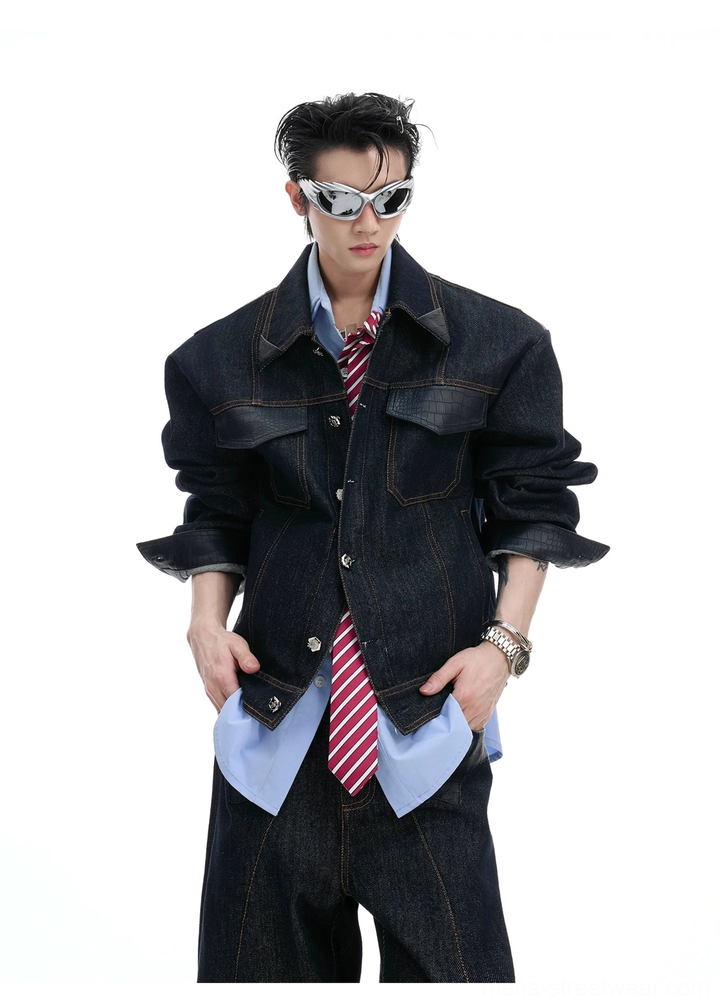 Male model styling a dark denim jacket and wide-leg jeans with a light blue shirt, red striped tie, leather watch, and silver sunglasses