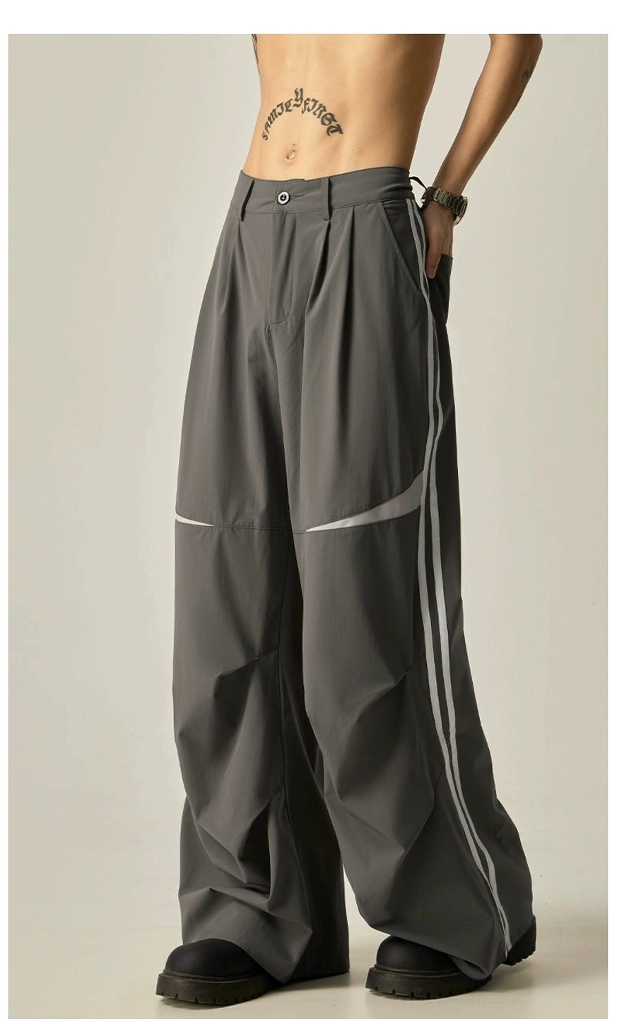 Dark gray baggy wide-leg track pants shown from the front side with pleated waist, double stripes, and white knee panels