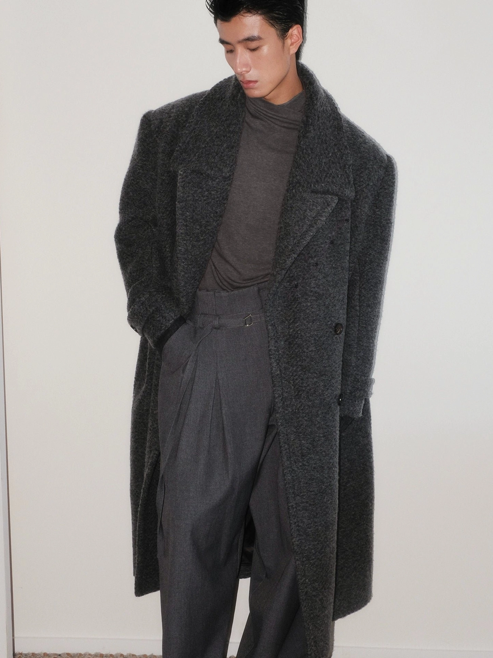 Men's dark gray bouclé wool oversized double-breasted long overcoat in front three-quarter view with peak lapels