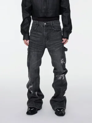 Male model wearing dark gray distressed stacked flare cargo denim jeans with ripped details and utility pocket front view