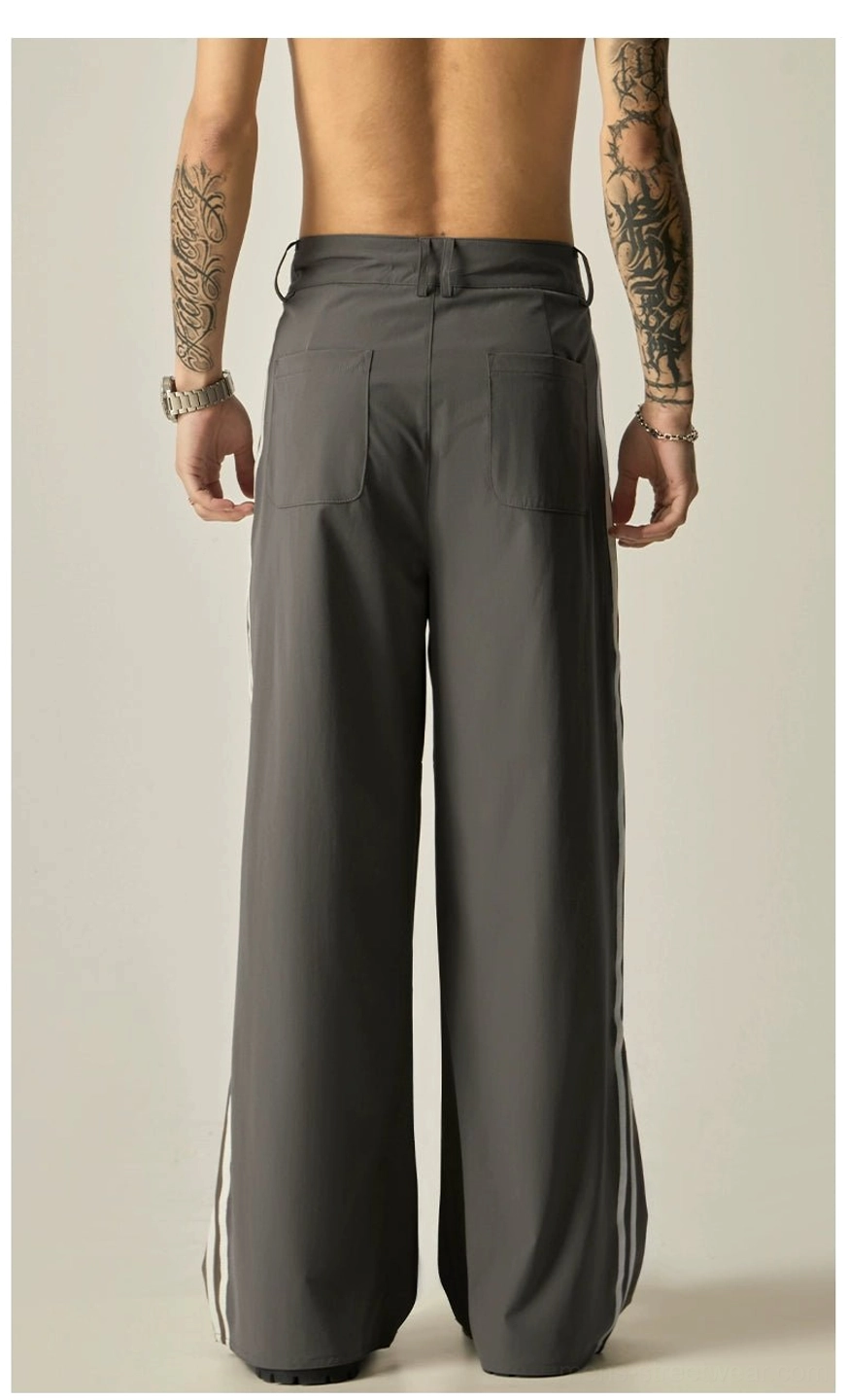 Back view of minimalist dark gray dual-stripe track pants with pleated waist, patch pockets, and smooth nylon fabric