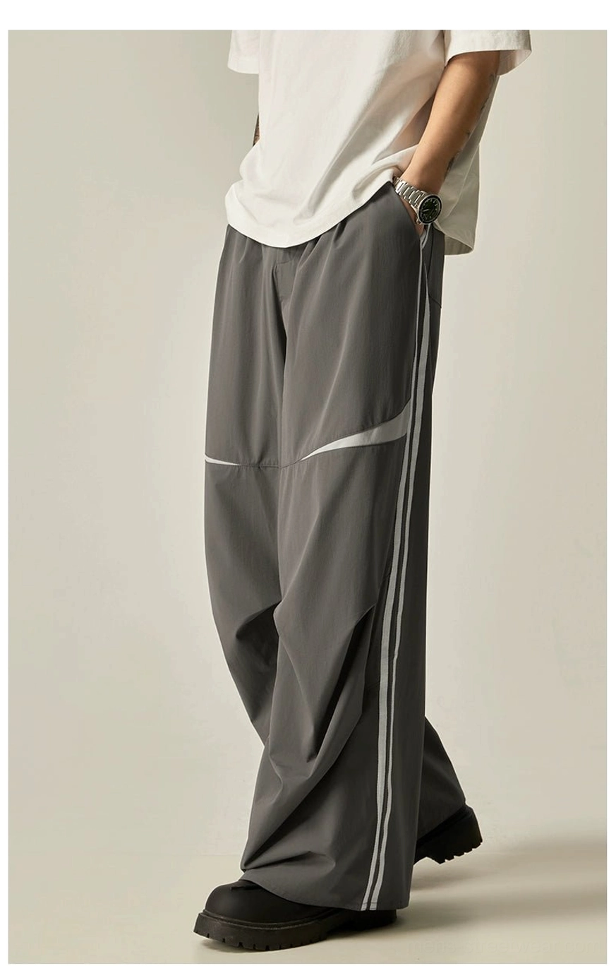 Dark gray wide-leg track pants with double white stripes, curved knee panels, and loose Korean streetwear styling