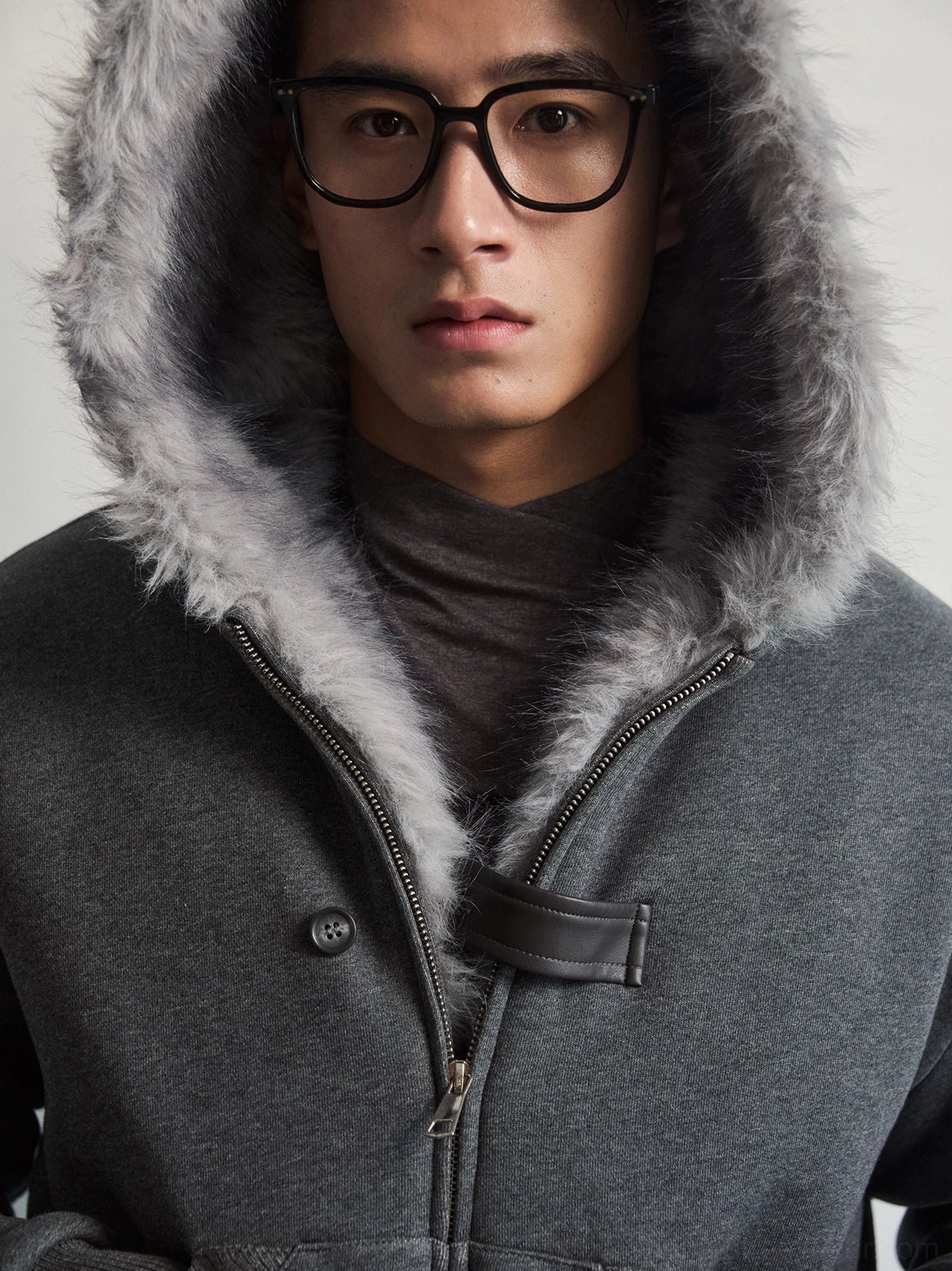 Close-up of gray faux fur hood trim metal zipper and leather throat latch on dark gray jacket