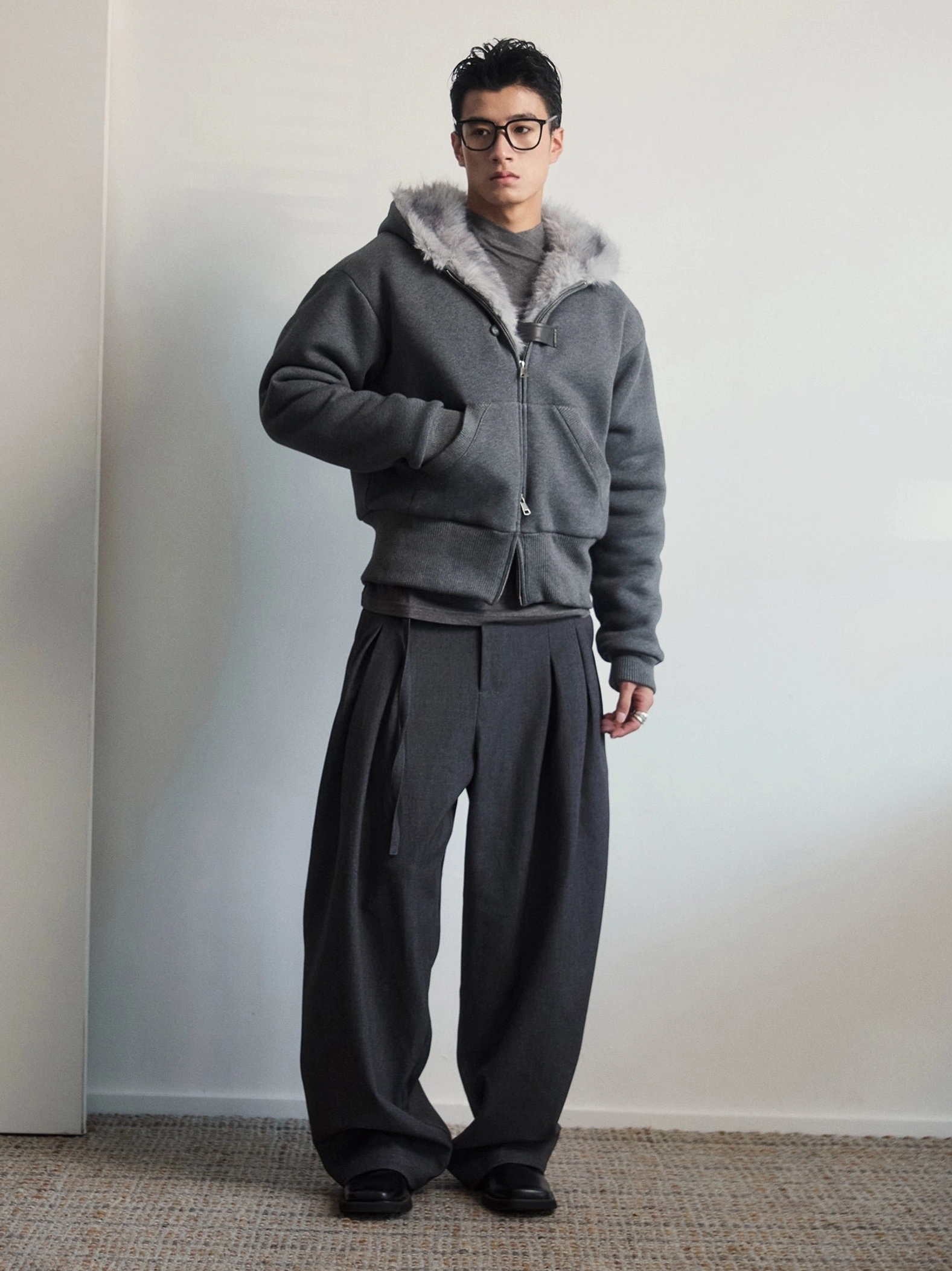 Dark gray faux fur hood jacket side view styled with wide leg trousers and black leather shoes