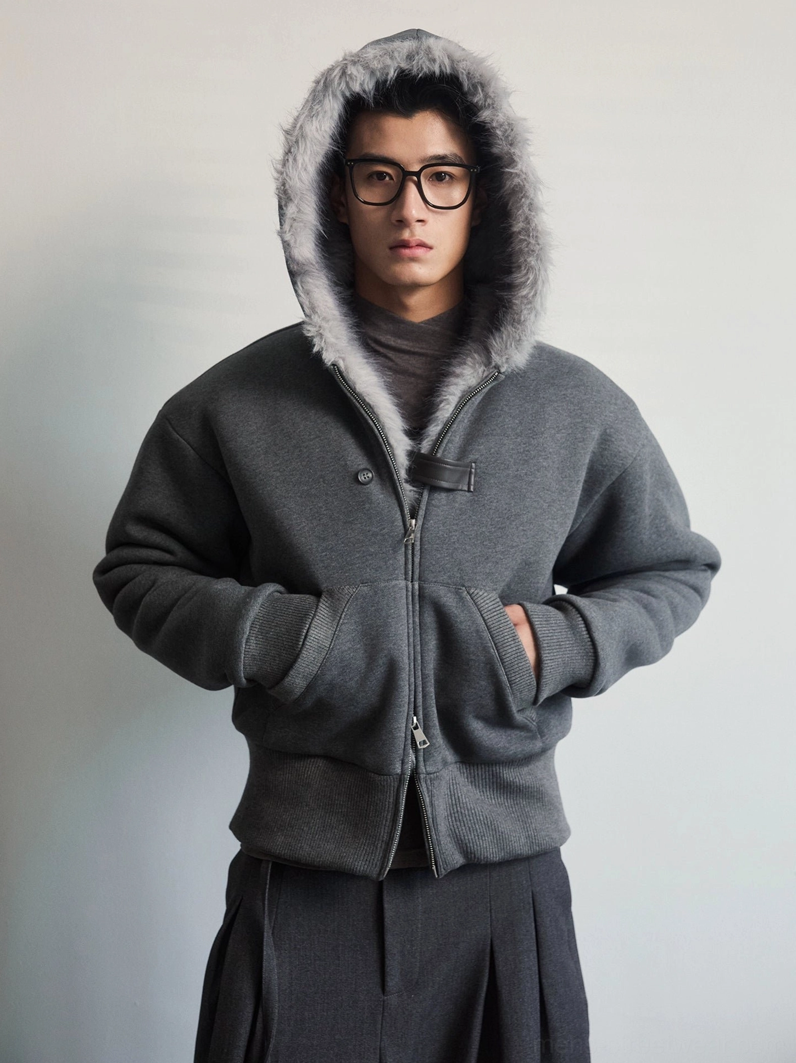Dark gray faux fur lined hood zip jacket front view worn by male model in minimalist studio