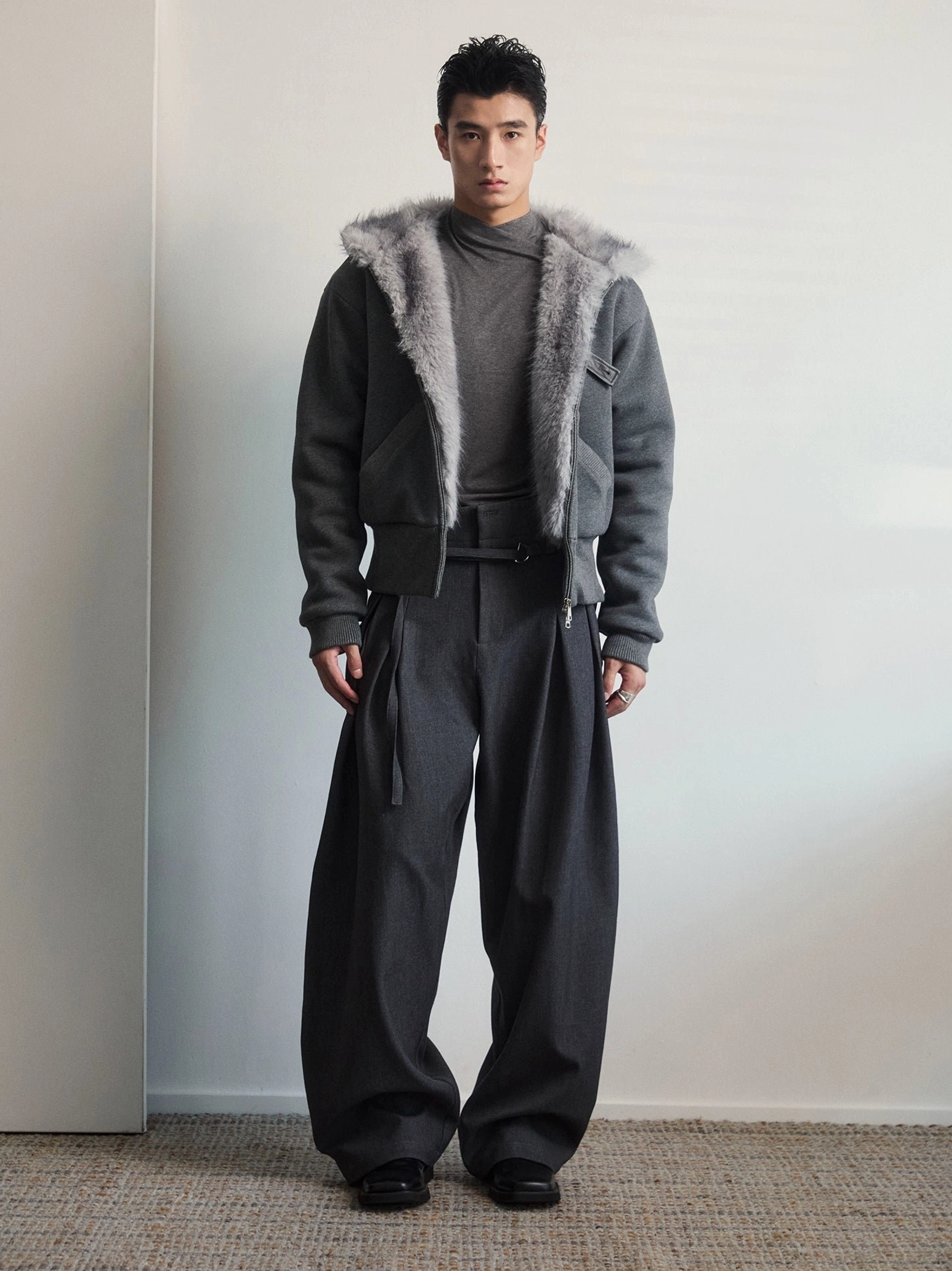 Mens dark gray faux fur lined hooded zip jacket open front layered over a high neck top