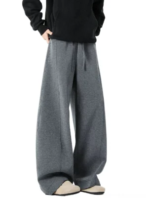 Dark gray heather wide-leg sweatpants with drawstring waist and extra-long pooled hem styled with black hoodie and beige slip-on shoes