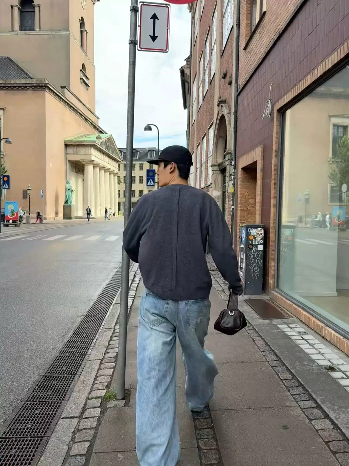 Dark gray relaxed henley knit cardigan worn with light blue wide-leg jeans on an urban downtown street