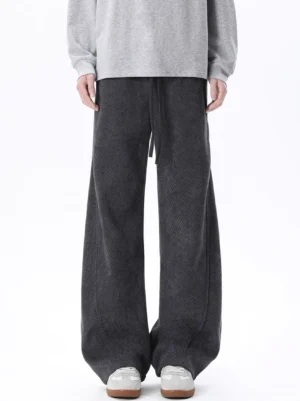 Dark gray herringbone wide-leg lounge trousers with drawstring waist shown from the front with a gray sweatshirt and retro sneakers