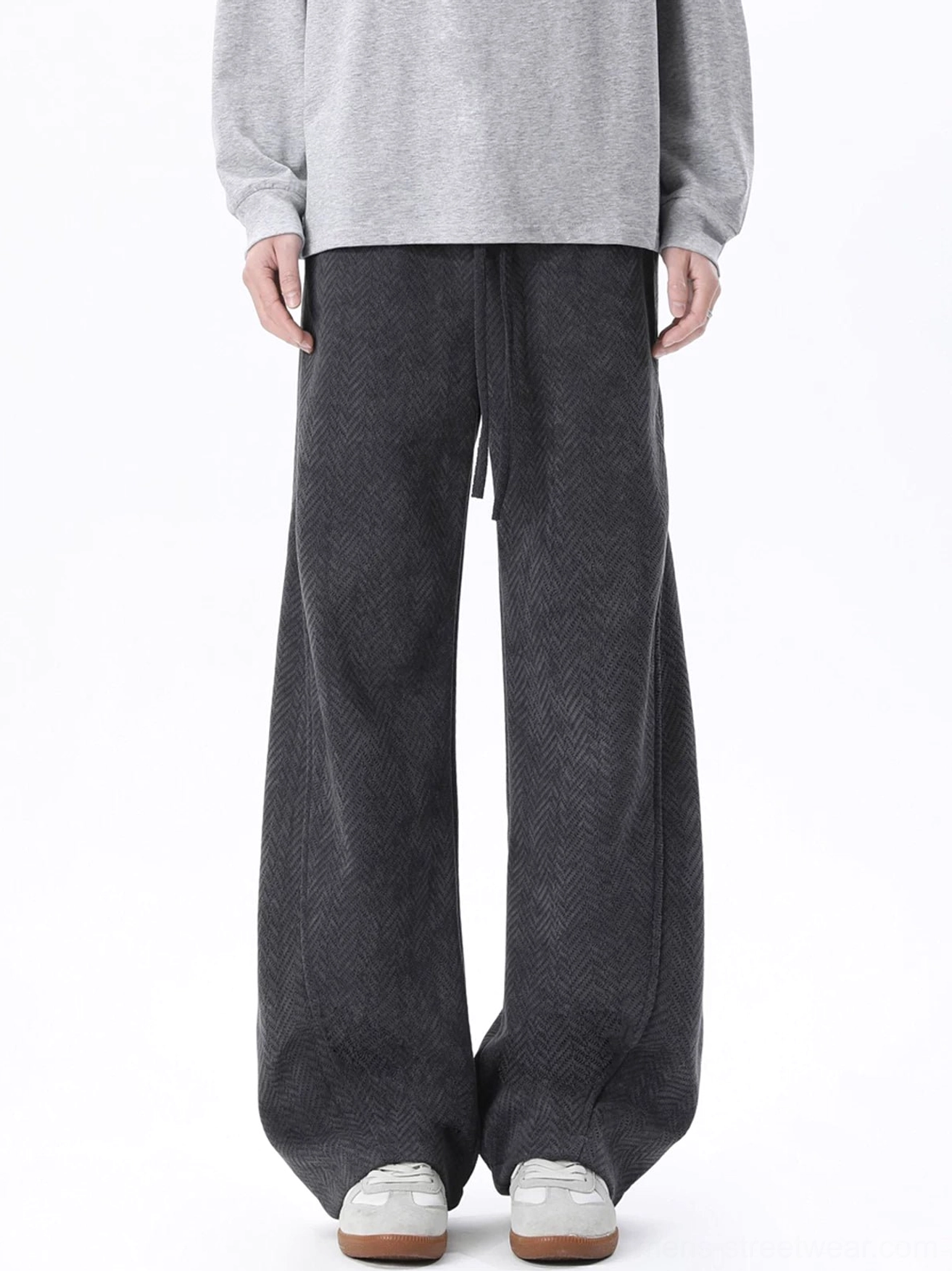 Dark gray herringbone wide-leg lounge trousers with drawstring waist shown from the front with a gray sweatshirt and retro sneakers