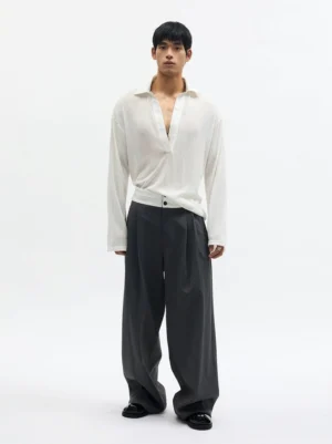 Dark gray high-rise wide-leg pleated trousers with ivory contrast waistband worn by male model front view