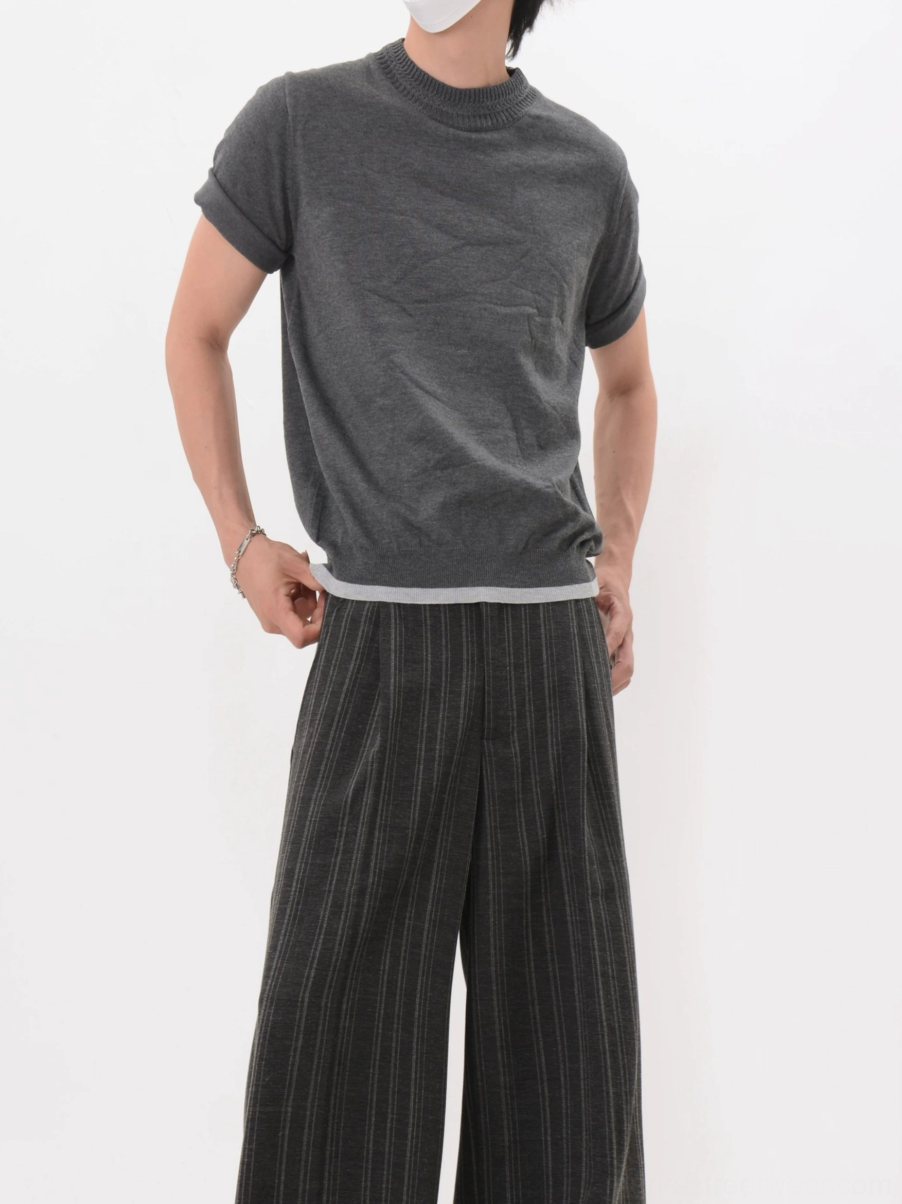 Dark gray knit mock neck short sleeve tee with contrast layered hem styled with solid wide leg trousers in a minimalist streetwear outfit