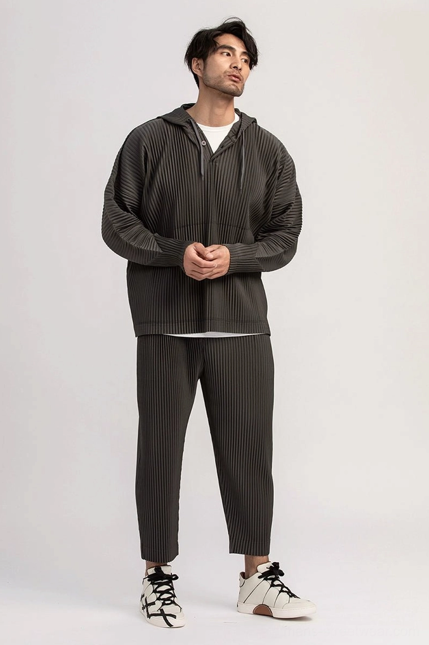 Dark gray men's pleated cropped pants paired with a loose zip-up hooded jacket for a modern layered Seoul streetwear look