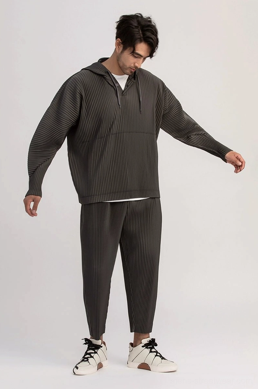 Dark gray pleated hoodie and matching cropped pants set for men with relaxed Korean streetwear proportions and casual sneakers