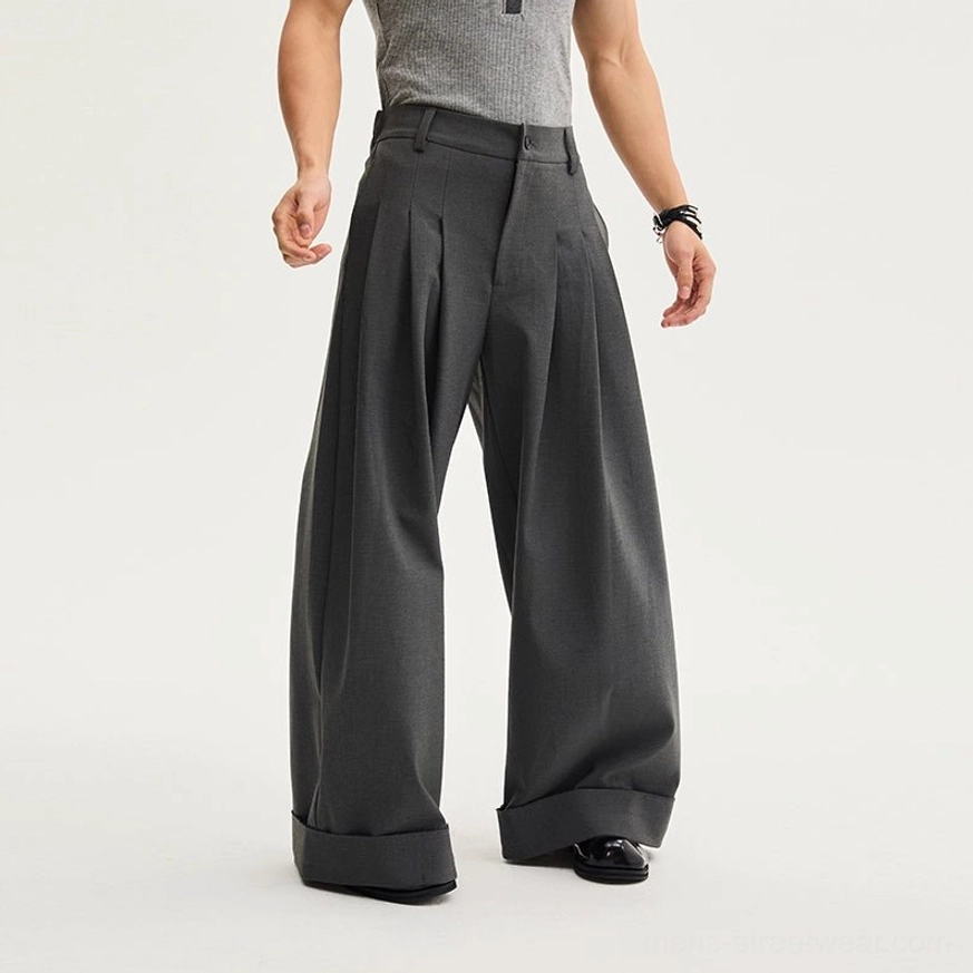 Dark gray oversized pleated wide-leg trousers styled with a gray tank top and rolled cuffs for a relaxed Acubi-inspired streetwear outfit